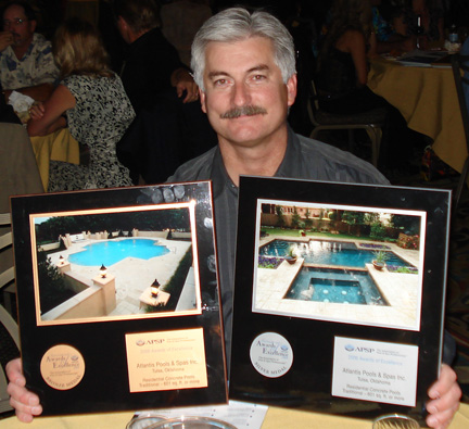 John Oliver holding two awards for swimming pool design. 