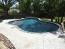Curved shape pool with a tanning ledge.