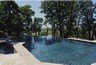 Infinity edge pool with stone coping edge around pool.