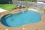 Free form pool with a raised stone wall and water falls.