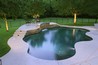 Free form pool with salt finish concrete decking and raised stone wall.