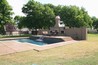 An angular pool with a fountain in the middle of a raised wall.