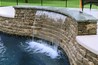 Close up view of a waterfall coming out of a stone wall.