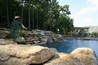 Boulder waterfall spilling into a spa and pool.