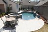 Small pool in small backyard with a round spa.