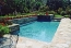 Straight line pool with raised planters and a stone deck.