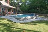 A swimming pool partially out of the ground with bi-level decking.