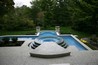 A vanishing edge pool flanked by two fire bowls on stone columns.