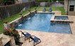 Pool and spa with a travertine deck and raised wall with waterfalls.