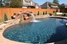 Boulder waterfall spilling into a pool with stone wall.