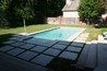 A rectangle pool with concrete decking pads surrounded by grass.